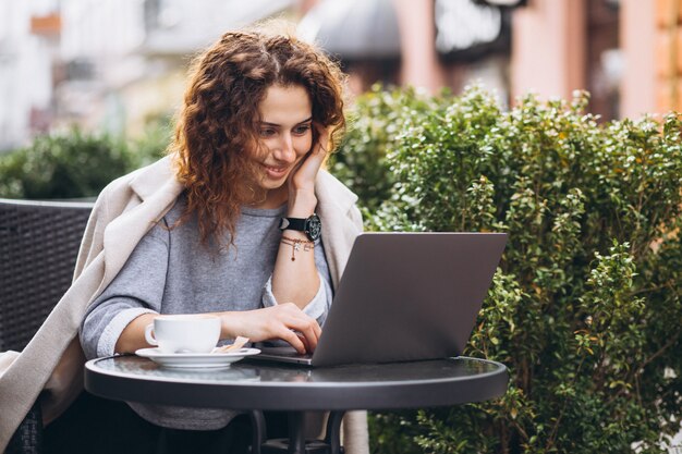 Joven empresaria trabajando en una computadora fuera del café