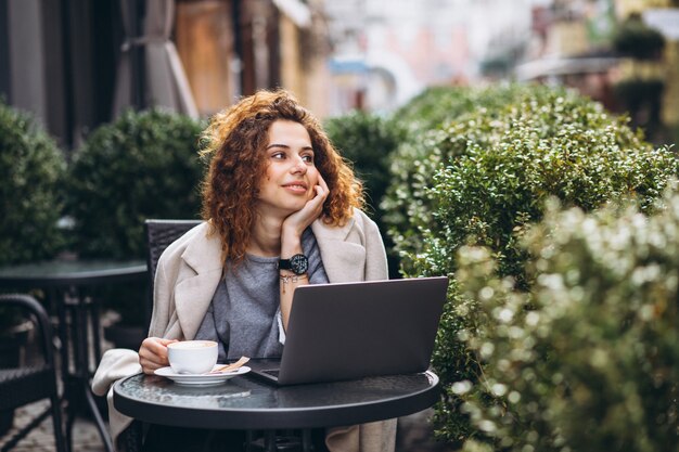 Joven empresaria trabajando en una computadora fuera del café