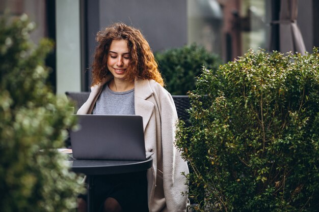 Joven empresaria trabajando en una computadora fuera del café