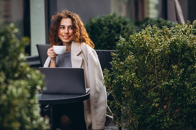 Joven empresaria trabajando en una computadora fuera del café