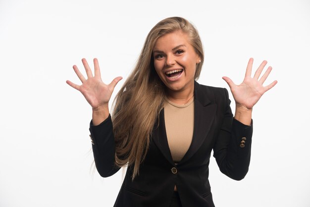 Joven empresaria en traje negro se ve alegre.