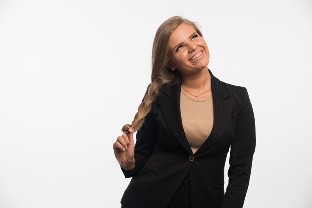 Joven empresaria en traje negro se ve feliz y sonriente.