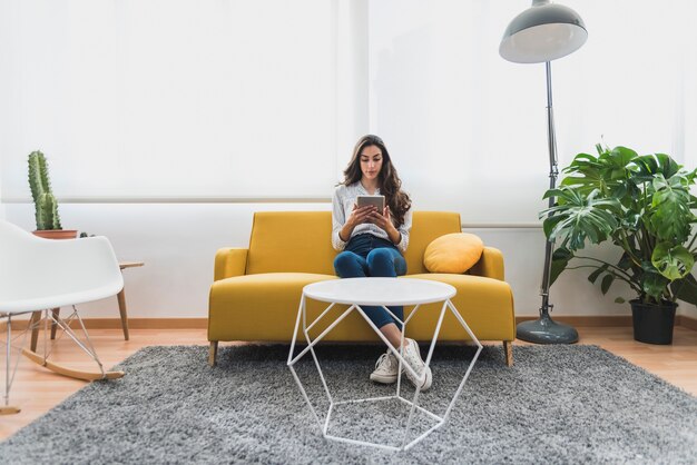 Joven empresaria usando su tableta sentada en el sillón