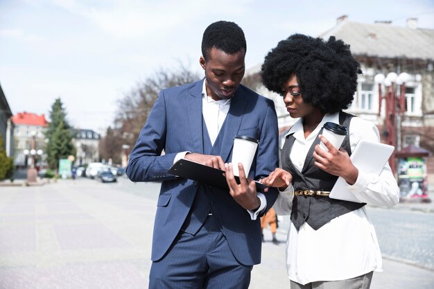 Joven empresario africano y empresaria mirando en el portapapeles