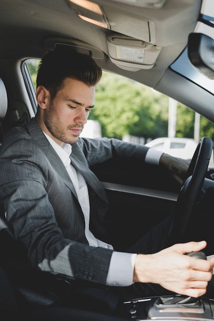 Joven empresario agarrando el engranaje en el coche