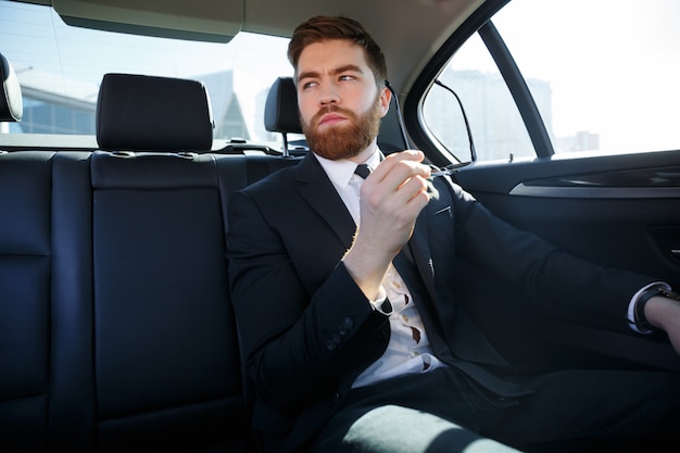 Joven empresario cansado sosteniendo anteojos y descansando