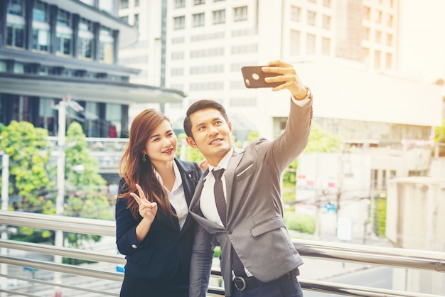 Joven empresario y colega al aire libre en el entorno urbano tomando un selfie