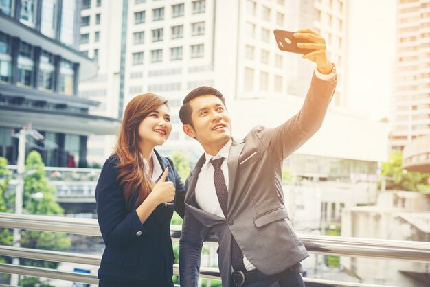 Joven empresario y colega al aire libre en el entorno urbano tomando un selfie