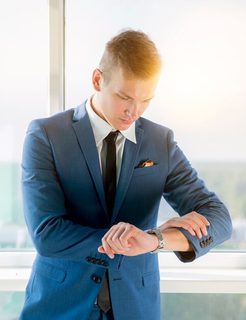 Joven empresario comprobando el tiempo en el reloj de pulsera