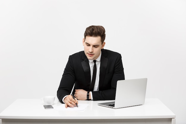 Joven empresario concentrado escribiendo documentos en el escritorio de oficina