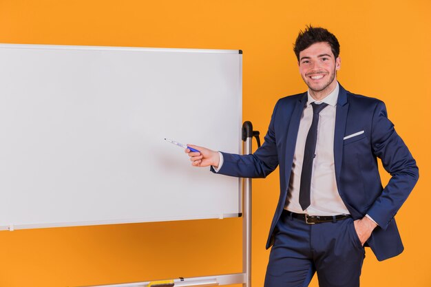 Joven empresario dando presentación contra un telón de fondo naranja