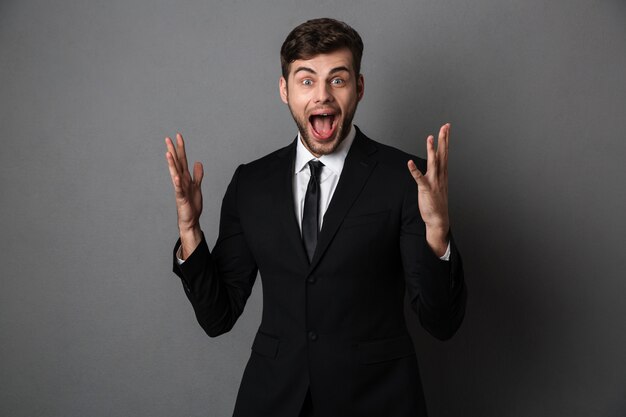 Joven empresario emocional gritando de pie con las palmas abiertas