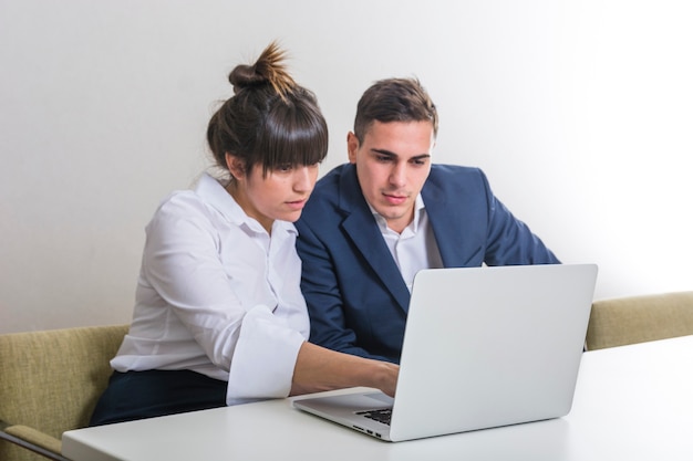 Joven empresario y empresaria usando laptop