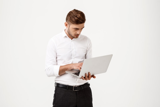 Joven empresario exitoso escribiendo en la computadora portátil.