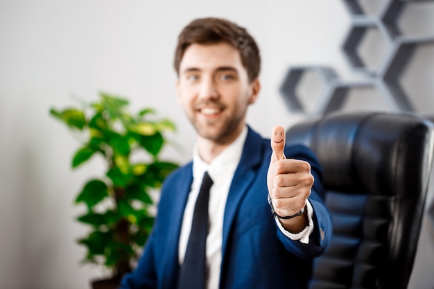 Joven empresario exitoso mostrando bien en el lugar de trabajo.