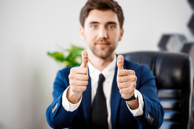 Foto gratuita joven empresario exitoso mostrando bien en el lugar de trabajo.