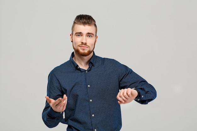 Joven empresario exitoso posando sobre pared gris.