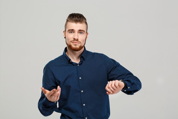 Joven empresario exitoso posando sobre pared gris.