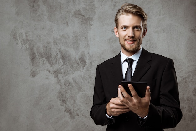 Joven empresario exitoso sonriendo, sosteniendo la tableta