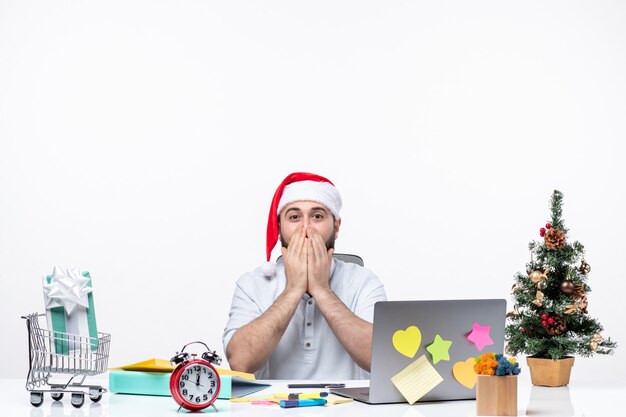 Joven empresario con expresión facial sorprendida en la oficina celebrando la Navidad y tapándose la boca