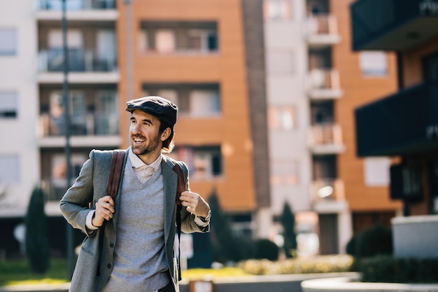 Joven empresario feliz con mochila caminando por la ciudad