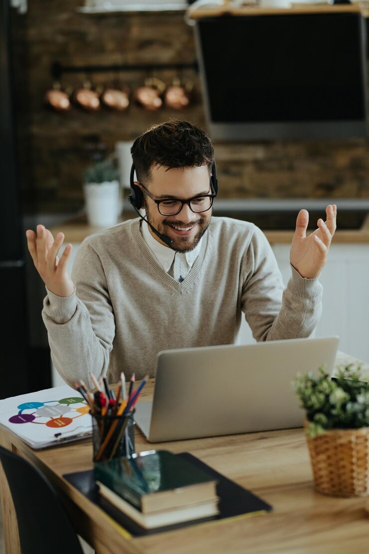 Foto gratuito joven empresario feliz que tiene una videollamada a través de una computadora en casa