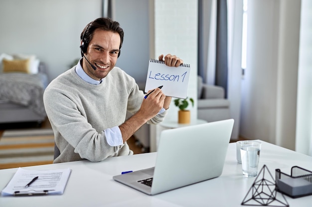 Joven empresario feliz trabajando en casa y dando clases de capacitación en línea sobre una computadora portátil