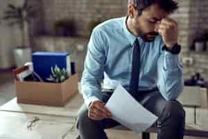 Foto gratuita joven empresario frustrado sosteniendo su cabeza con dolor después de ser despedido en el trabajo