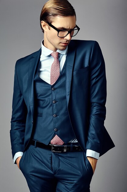 Joven empresario guapo elegante modelo masculino en un traje y gafas de moda, posando en el estudio