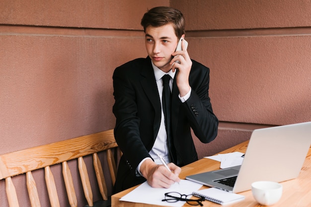 Foto gratuita joven empresario hablando por teléfono en la oficina