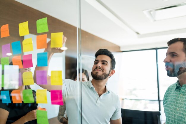 Joven empresario de intercambio de ideas con compañeros de trabajo en reunión en la oficina