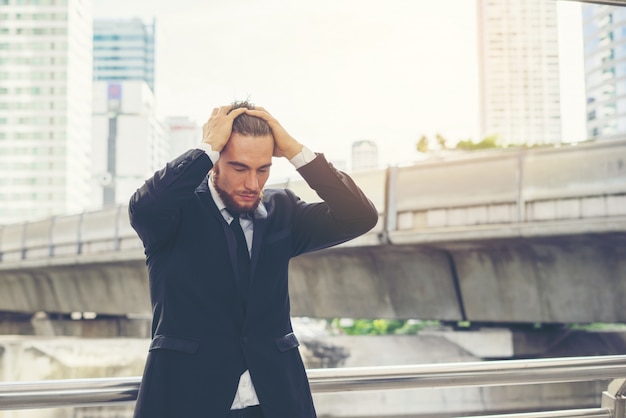 Foto gratuita joven empresario mano sobre la cabeza se sienten sobre el trabajo.