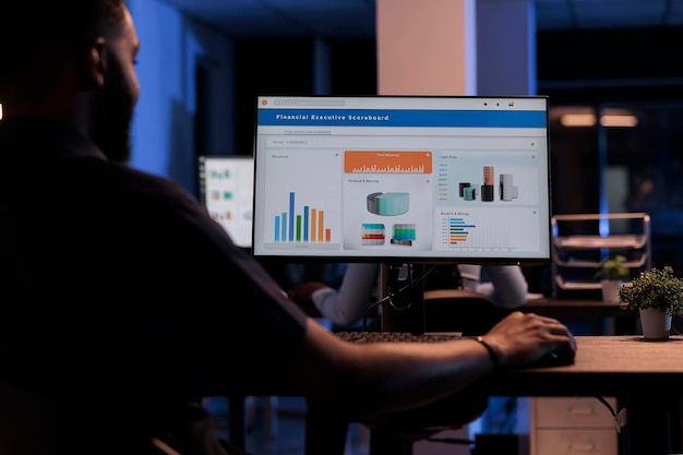 Joven empresario mirando el monitor de la computadora con gráficos, analizando información estadística y datos para crear un informe de proyecto, haciendo investigación financiera. Pantalla de pc con presentación en red.