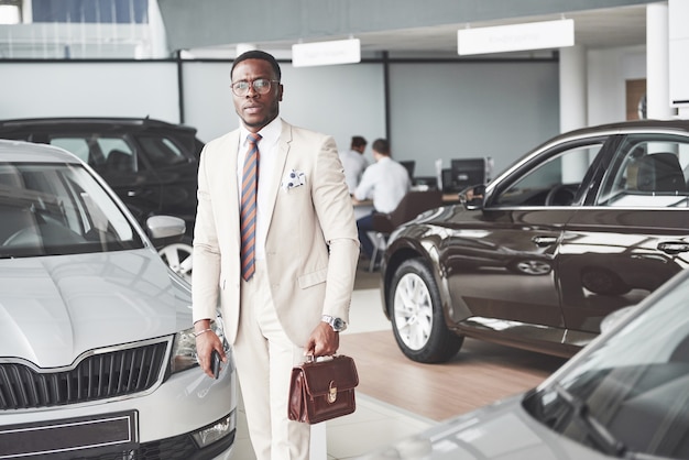 Joven empresario negro en el salón del automóvil. Concepto de venta y alquiler de coches.