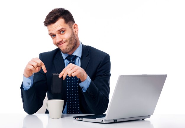 Joven empresario poniendo su teléfono dentro de la taza de café
