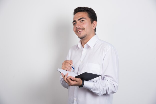 Joven empresario con portátil posando sobre fondo blanco.