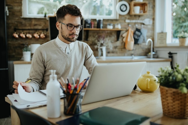 Joven empresario que usa una computadora portátil mientras trabaja en casa