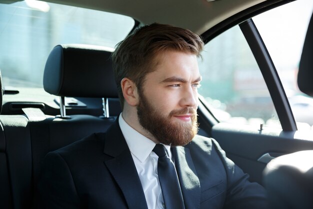 Joven empresario sonriente sentado en un auto