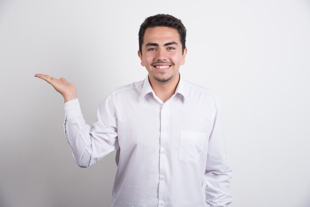 Joven empresario sosteniendo un espacio abierto sobre fondo blanco.