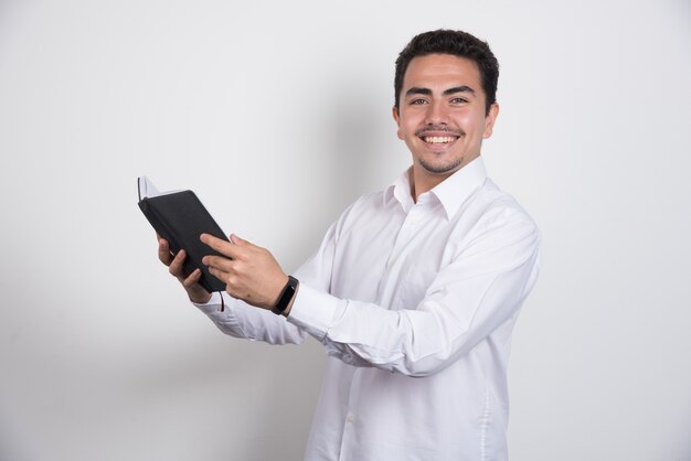 Joven empresario sosteniendo portátil sobre fondo blanco.