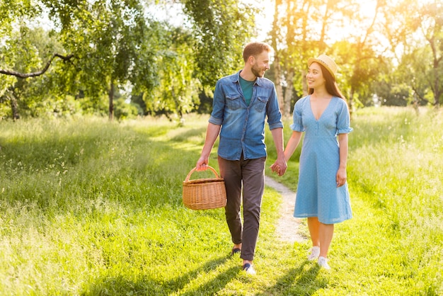 Joven enamorada multirracial caminando en el parque tomados de la mano