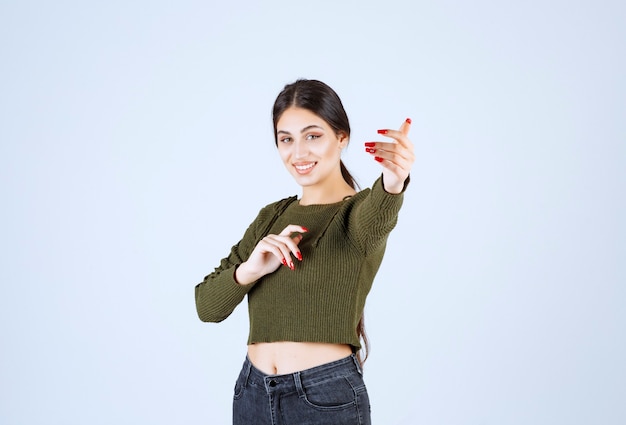 Una joven y encantadora modelo en verde llamando a alguien para que venga