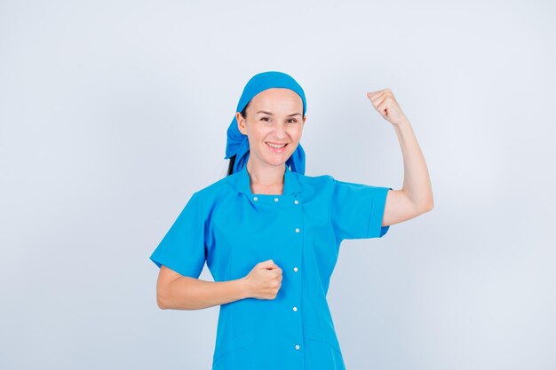 Una joven enfermera sonriente está levantando su puño sobre fondo blanco.