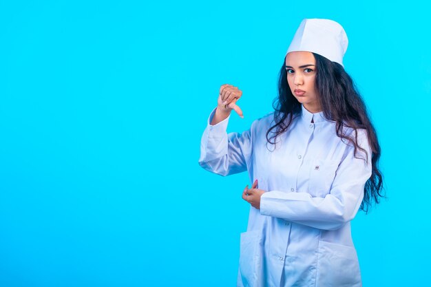 Joven enfermera en uniforme aislado parece deprimida y hace un signo negativo
