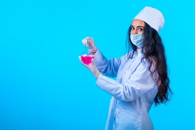 Joven enfermera en uniforme aislado sosteniendo un matraz de prueba