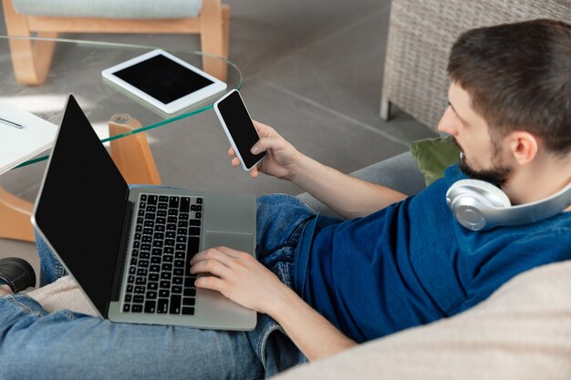 Joven enfocado estudiando en casa durante cursos en línea o información gratuita por sí mismo