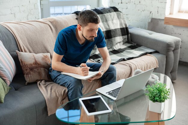 Joven enfocado estudiando en casa durante cursos en línea o información gratuita por sí mismo