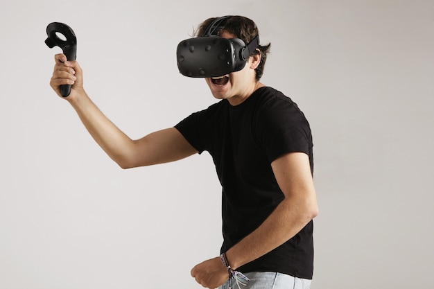 Joven enojado en auriculares vr y camiseta de algodón negro jugando un juego de lucha