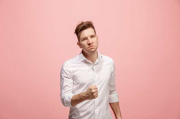 Joven enojado emocional gritando en pared rosa