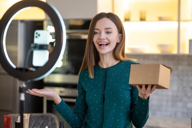 Joven entrenadora de belleza sonriente que presenta nuevos productos de belleza a la audiencia en línea